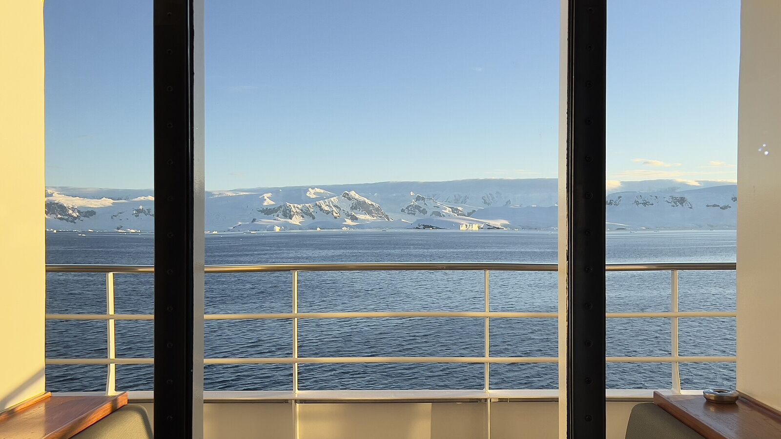 Uitzicht vanaf het balkon van een expeditieschip op besneeuwde bergen van het Antarctisch Schiereiland