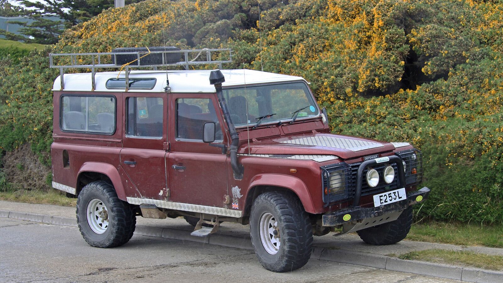 Rode Land Rover Defender geparkeerd langs een weg in Stanley op de Falklandeilanden