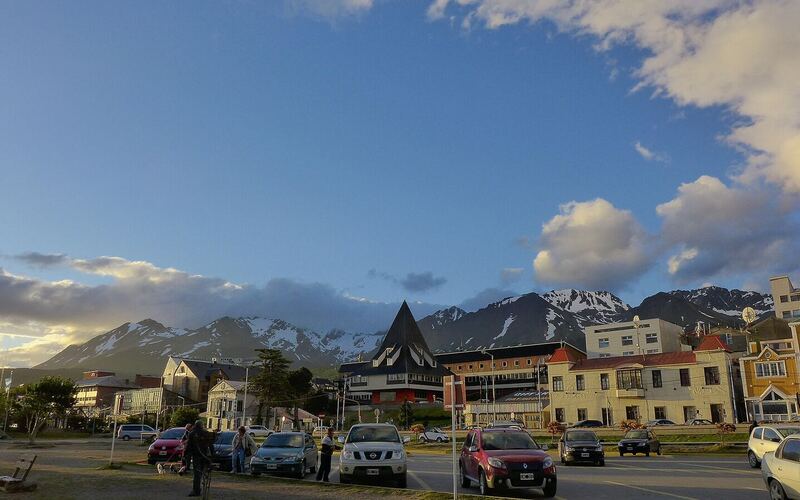 Straat in het centrum van Ushuaia met gekleurde gebouwen en besneeuwde bergen op de achtergrond