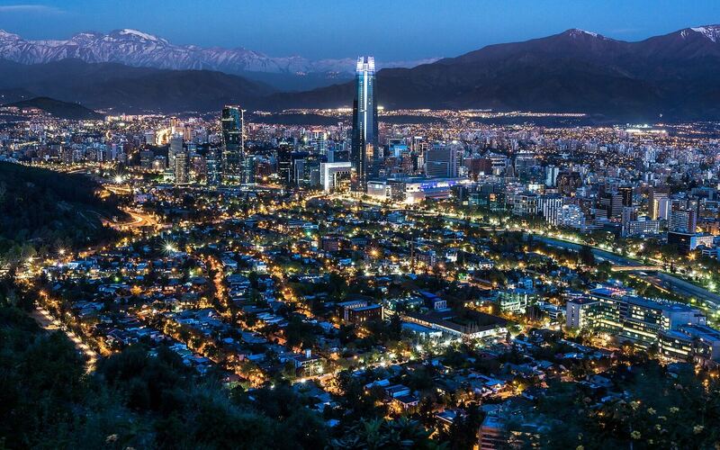 Santiago de Chile in het blauwe uur, met verlichte straten, de Gran Torre en de Andes op de achtergrond
