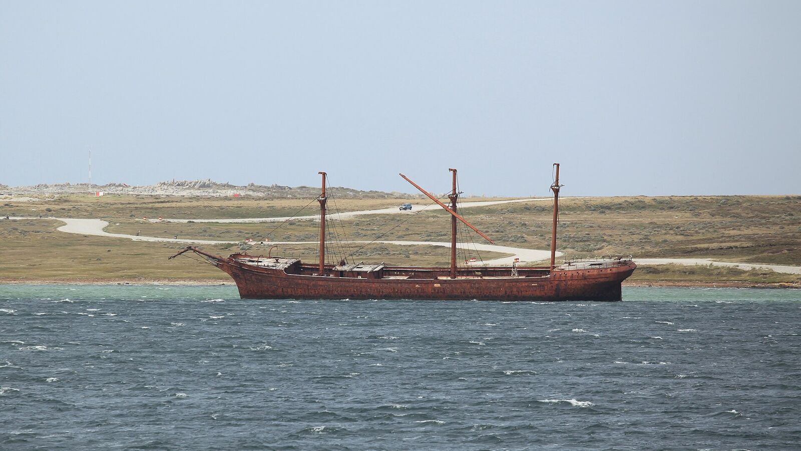 Het driemaster-wrak Lady Elizabeth ligt scheef in Whalebone Cove met het kale land rond Stanley op de achtergrond